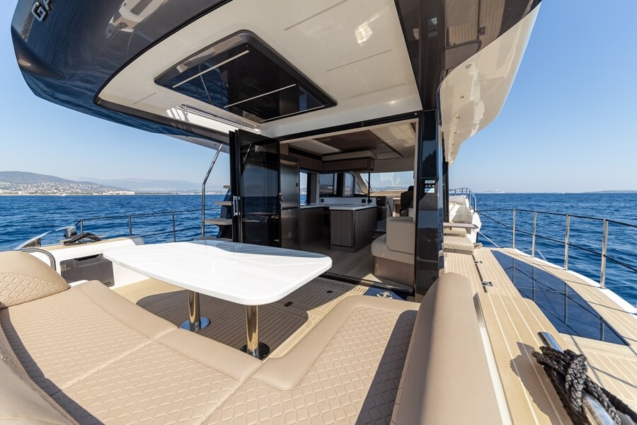 Yacht aft deck with lounge seating and dining table on open water